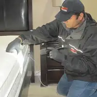 Bed bug inspection technician checking a mattress and bed frame for signs of infestation in Philadelphia, PA