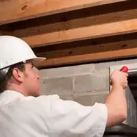 Termite inspection technician checking a basement wall and framing for termite activity in Philadelphia, PA
